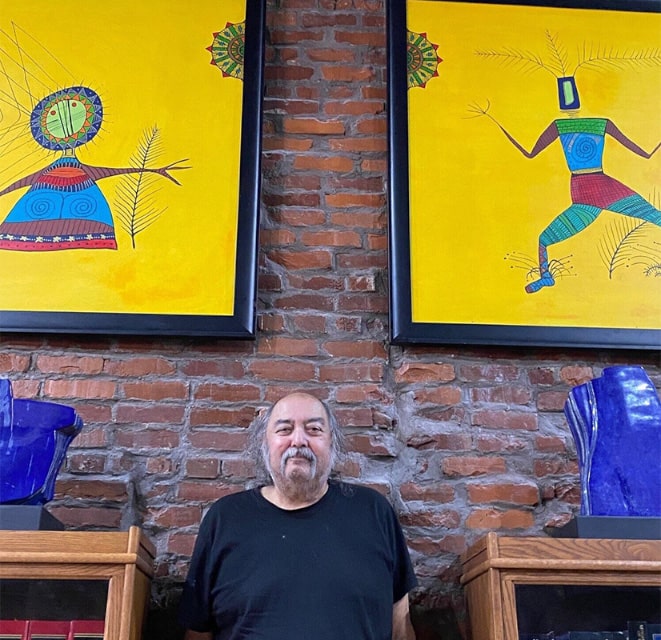 Alan Syliboy posing in front of his artwork at MacGillivray Law office in New Glasgow